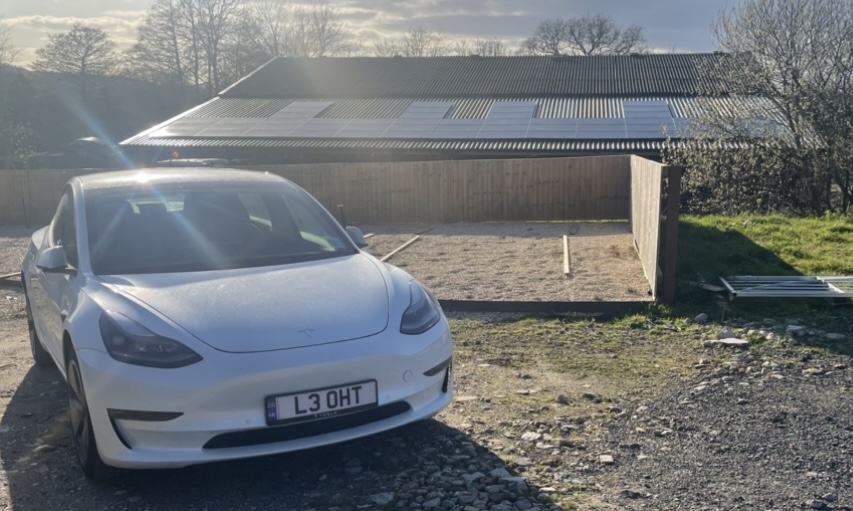 Leoht Tesla infront of a commercial solar install